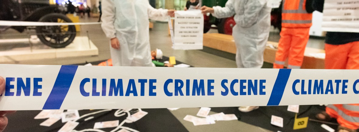 'Climate crime scene' hazard tape in front of protesters dressed in haz-mat suits inside the Science Museum
