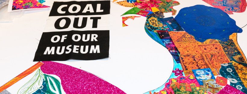 Black and white 'Coal out of our Museum' sign arranged on a fabric collage